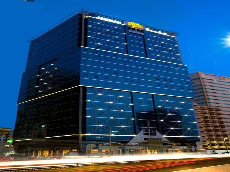 Jannah Burj Al Sarab Hotel Abu Dhabi Exterior foto The photo shows a modern skyscraper with a sleek, glass facade, reflecting a night sky. The building is illuminated with bright lights, making it stand out against the evening backdrop. The structure has multiple floors and appears to be part of a co